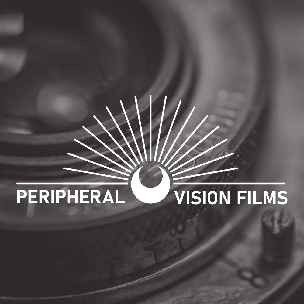 Black and white image featuring the Peripheral Vision Films logo. The logo’s semi-circular design with radiating lines stands prominently above the text "Peripheral Vision Films." In the background, a close-up of slightly blurred camera lenses enhances the visual depth.