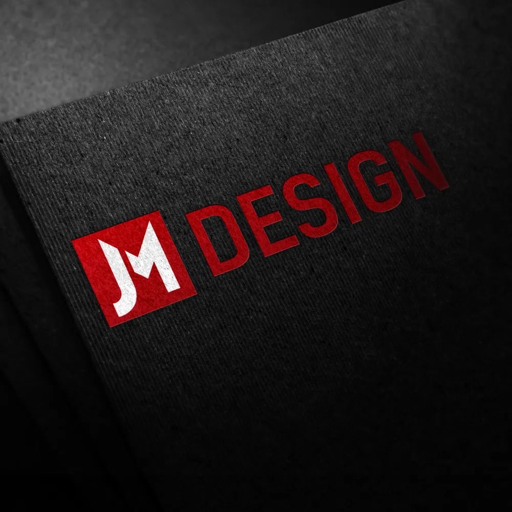 The image showcases a black textured surface with the "JM DESIGN" logo. The letters "JM" are in white within a red square, while the word "DESIGN" in red sits to the right of it. This bold, modern font encapsulates John McHugh Design's commitment to innovative brand design.