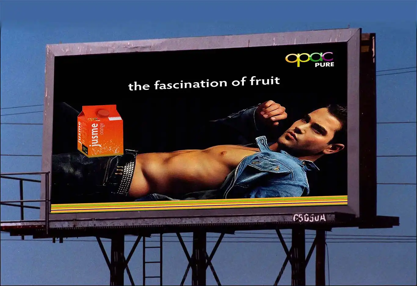 Jusme Juice Drink Range by-OPAC-billboard A billboard ad shows a shirtless man reclining, wearing an unbuttoned denim jacket and jeans. Next to him is a juice box with eye-catching packaging design. The text reads, "the fascination of fruit" along with the brand name "opgc PURE.
